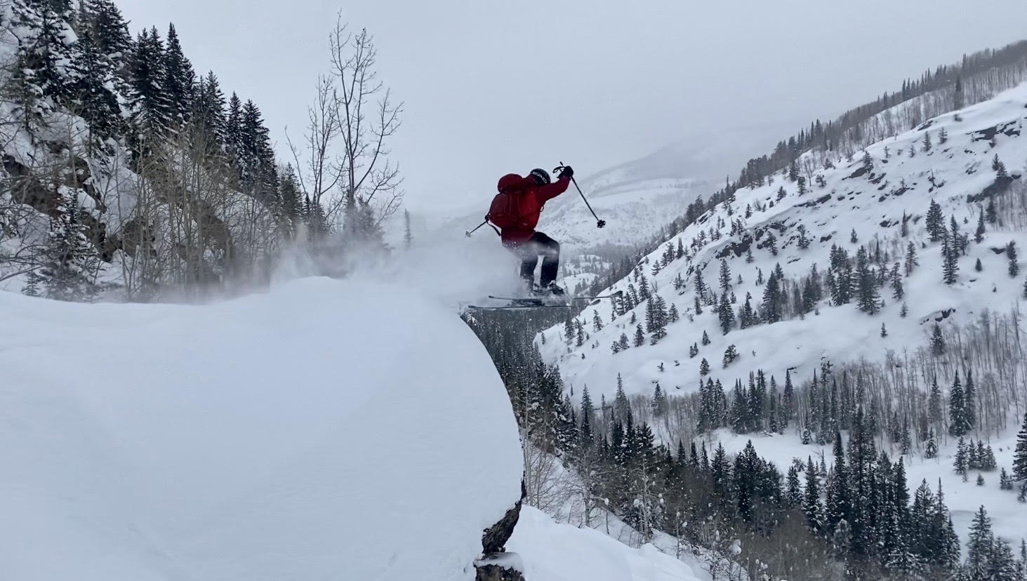Person skiing off of a very large boulder