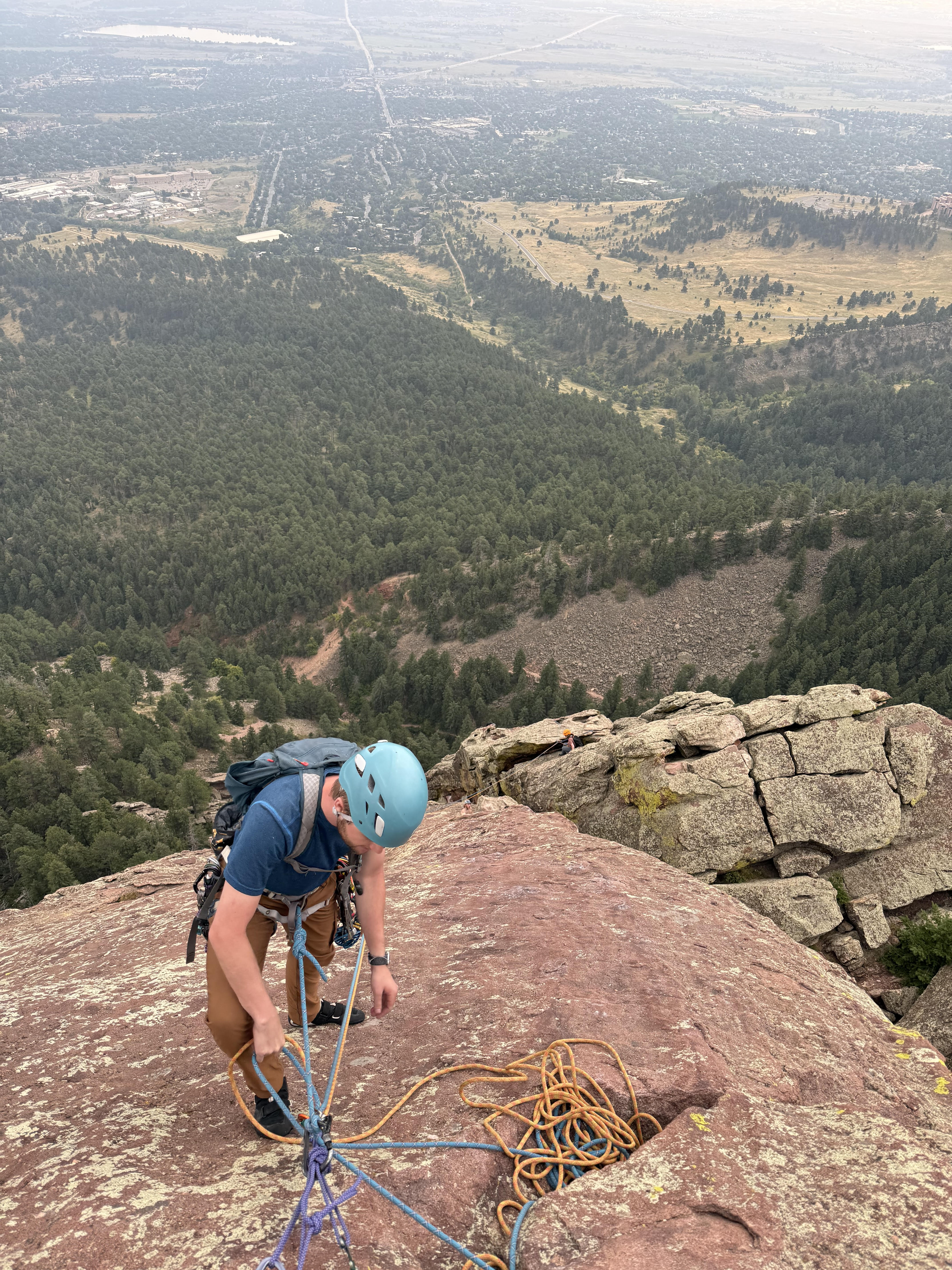 Person belaying up climbers from the top of a flatiron